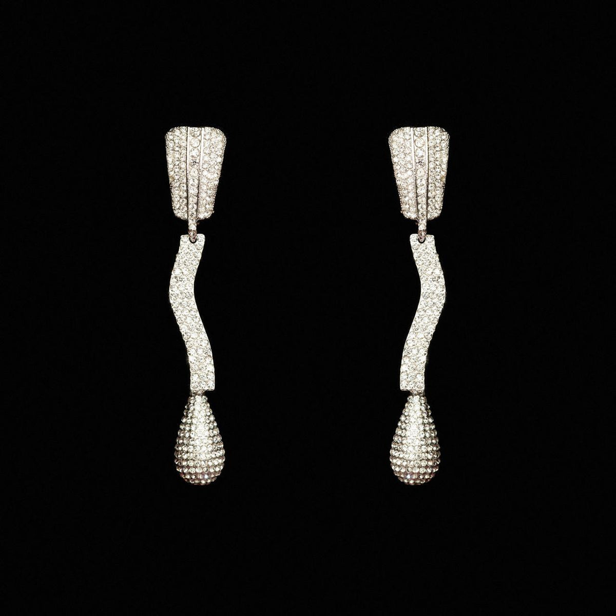 Sculptural silver-tone drop earrings with a wave-shaped crystal pave bar and teardrop