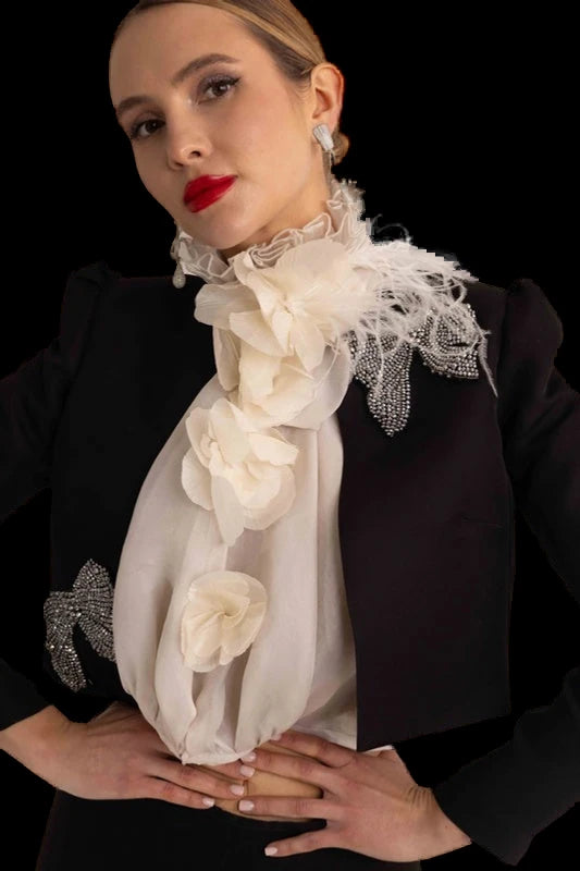 A black cropped jacket and flared trousers with a ruffled organza scarf.