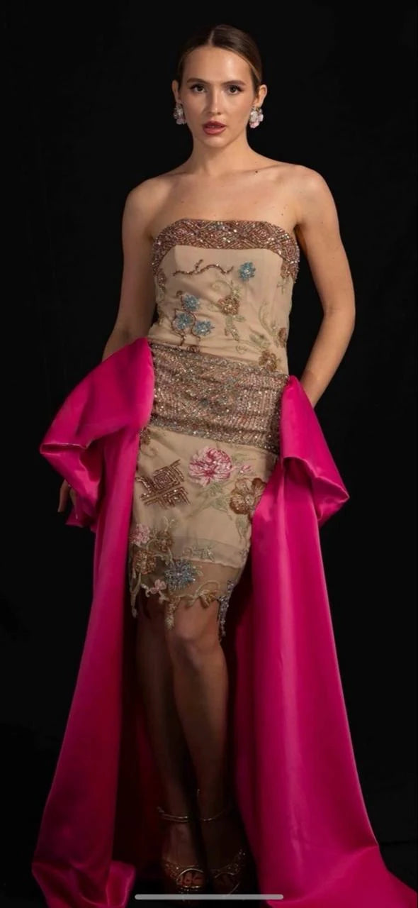 A beaded nude gown with a fuchsia satin drape falling from the waist.