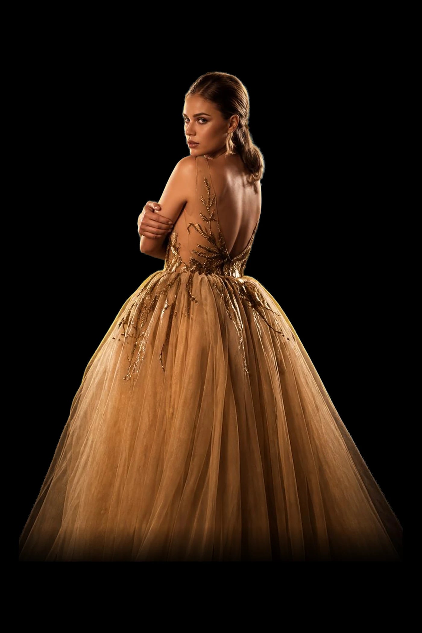A gold gown embroidered with branches over a full tulle skirt, seen from behind.