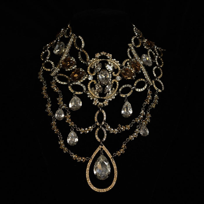 Wide antiqued gold bib necklace with smoky and clear crystals and a large pear-cut pendant