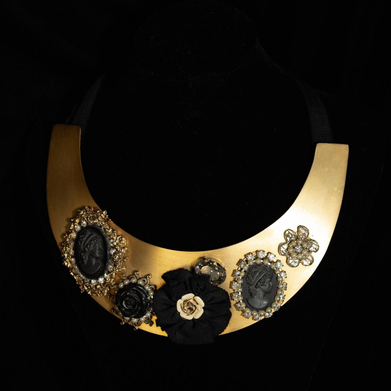 Wide matte gold crescent collar necklace set with black cameos and a carved black rose