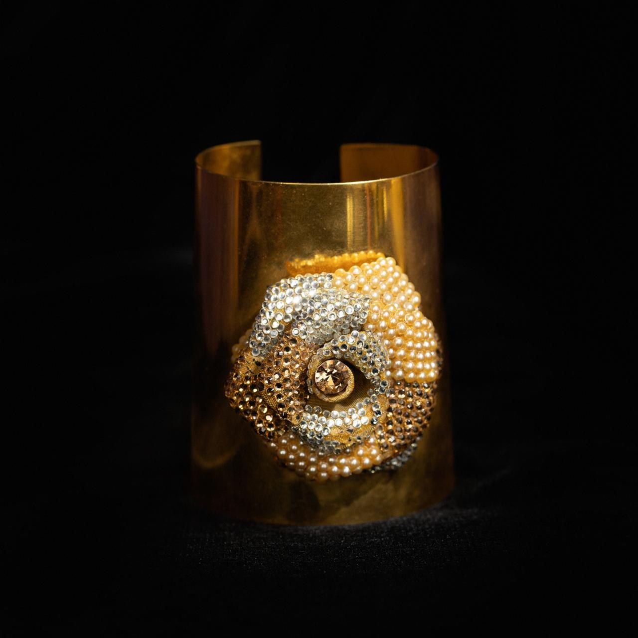 Wide gold-tone cuff bracelet with a large spiral shell worked in seed pearls and crystals