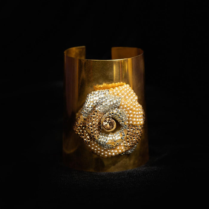 Wide gold-tone cuff bracelet with a large spiral shell worked in seed pearls and crystals