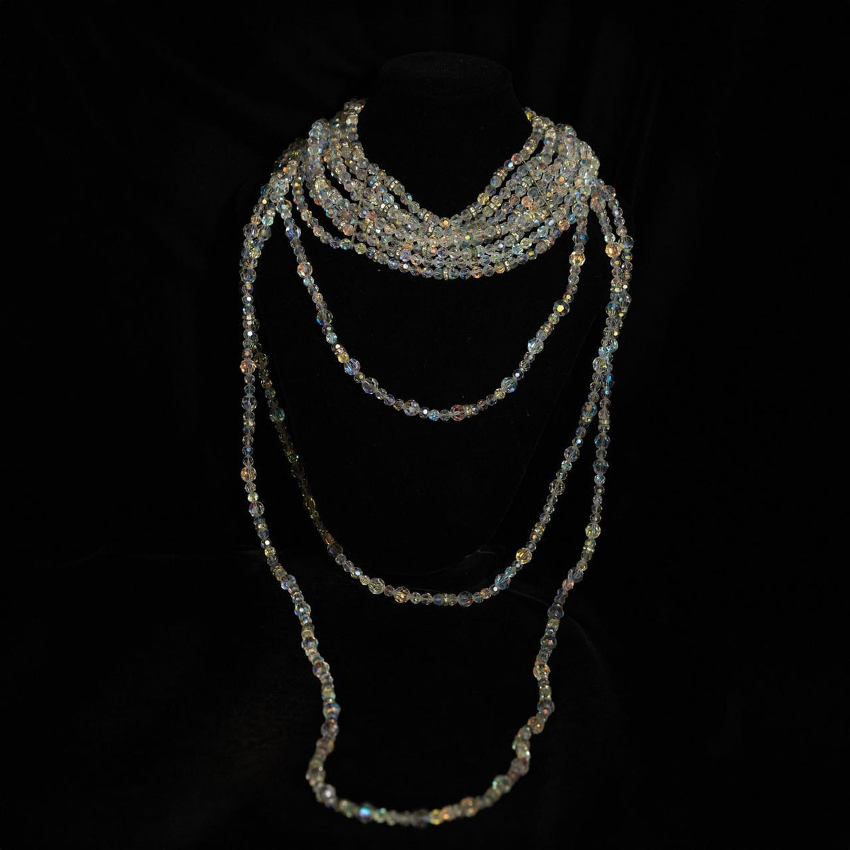 Multi-strand necklace of small iridescent crystal beads twisted at the throat