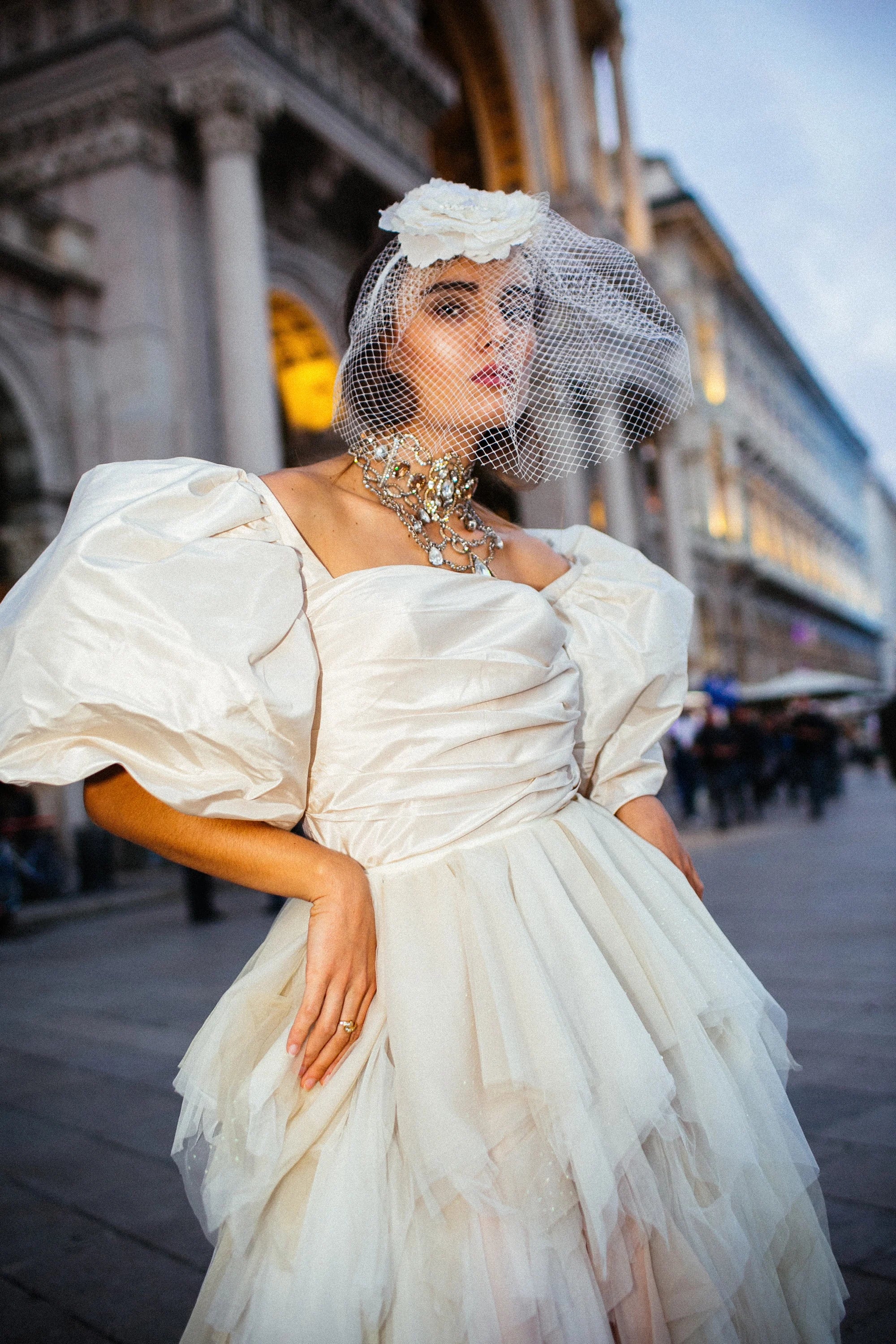 An ivory tulle ballgown with full puff sleeves, photographed in the piazza before the Duomo, Milan.