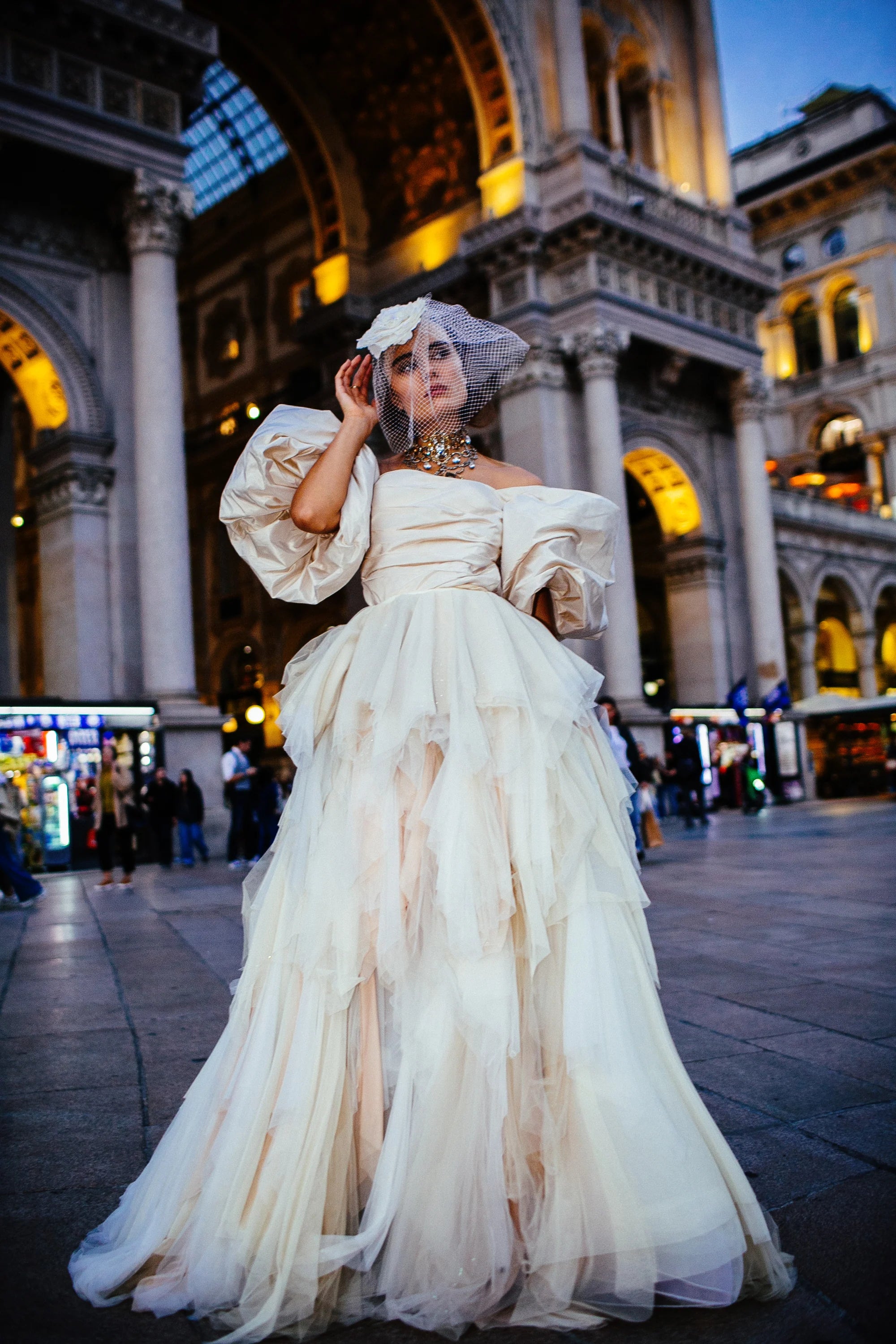An ivory tulle ballgown with full puff sleeves, photographed in the piazza before the Duomo, Milan.