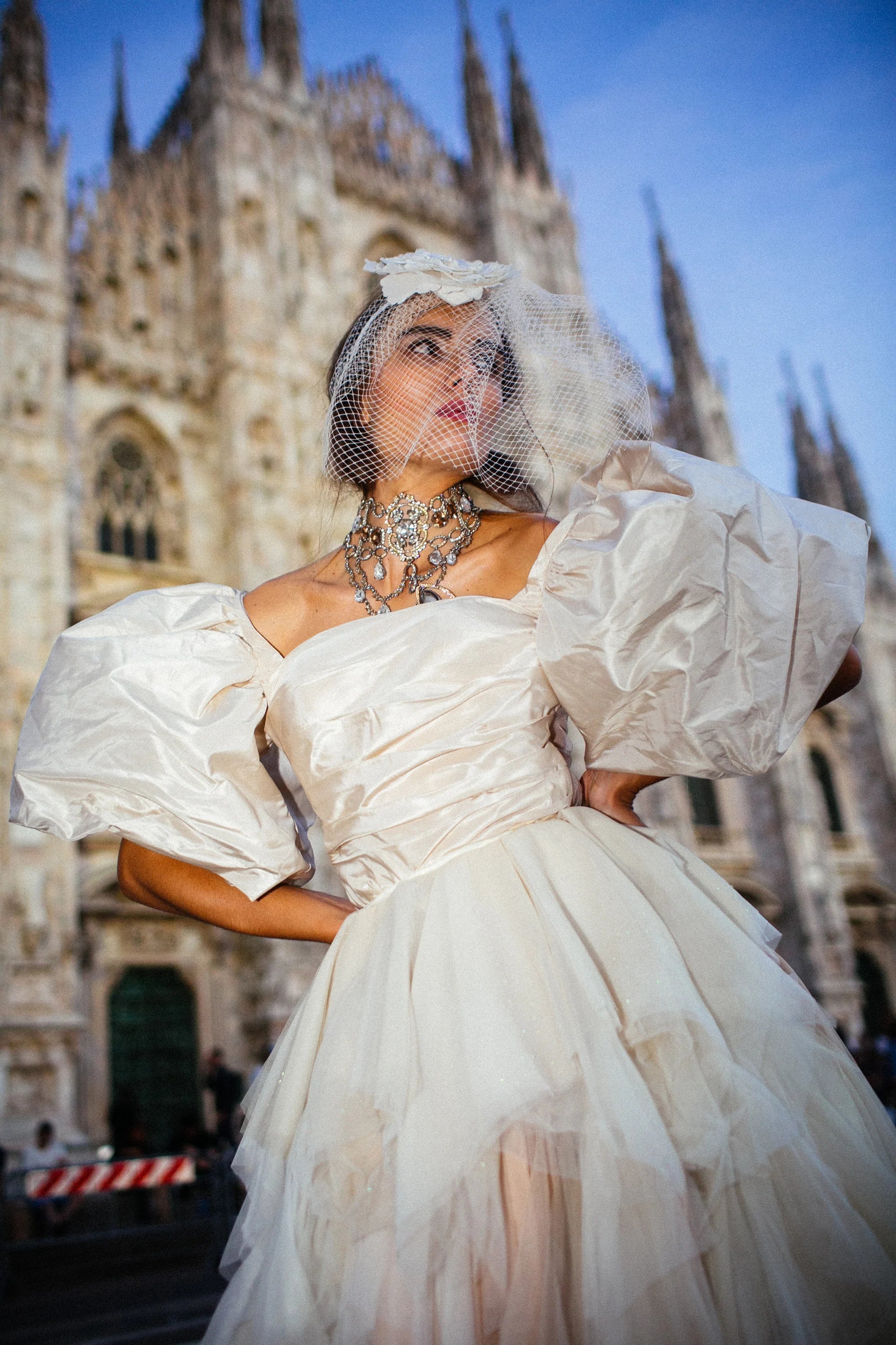 An ivory tulle ballgown with full puff sleeves, photographed in the piazza before the Duomo, Milan.