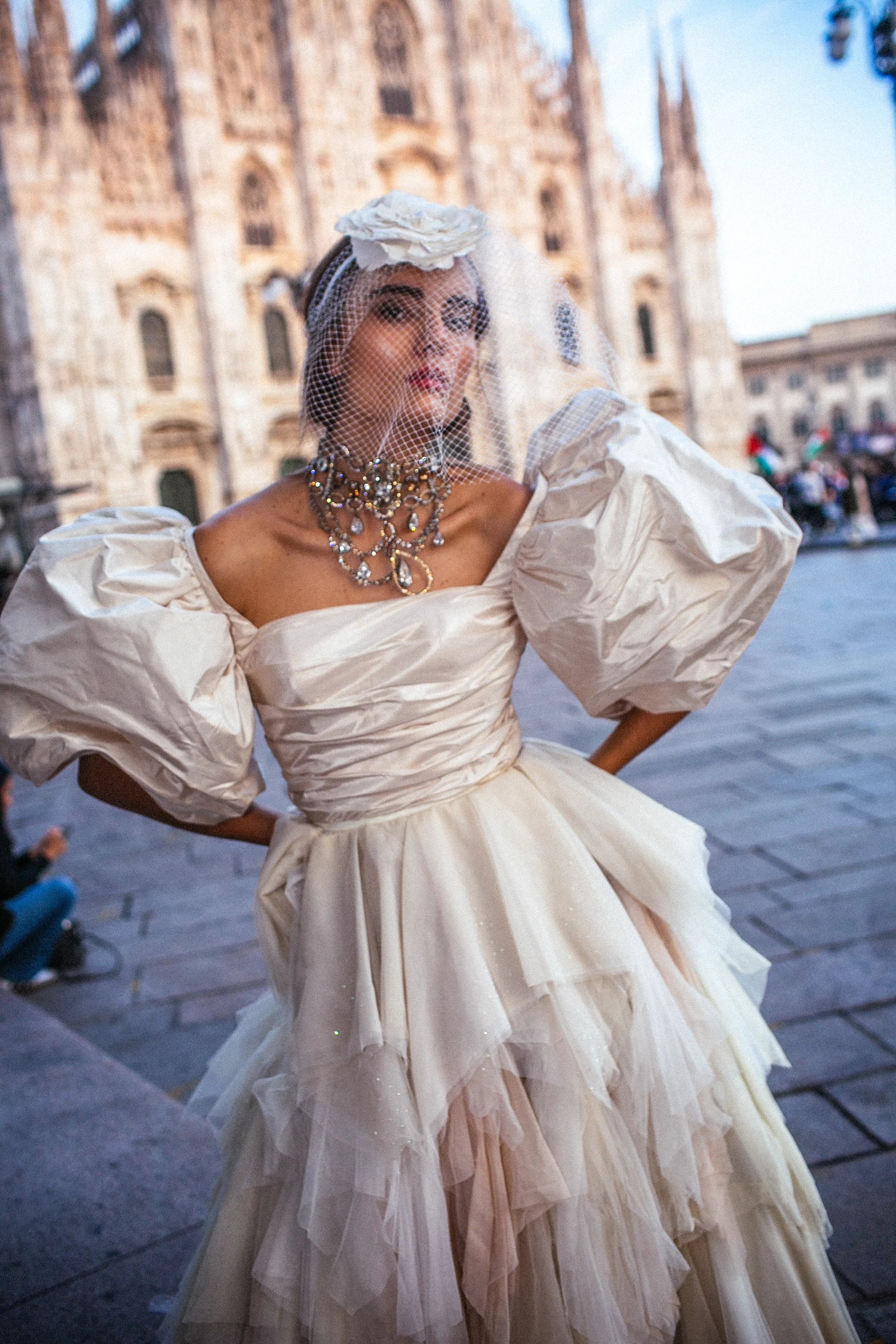 An ivory tulle ballgown with full puff sleeves, photographed in the piazza before the Duomo, Milan.
