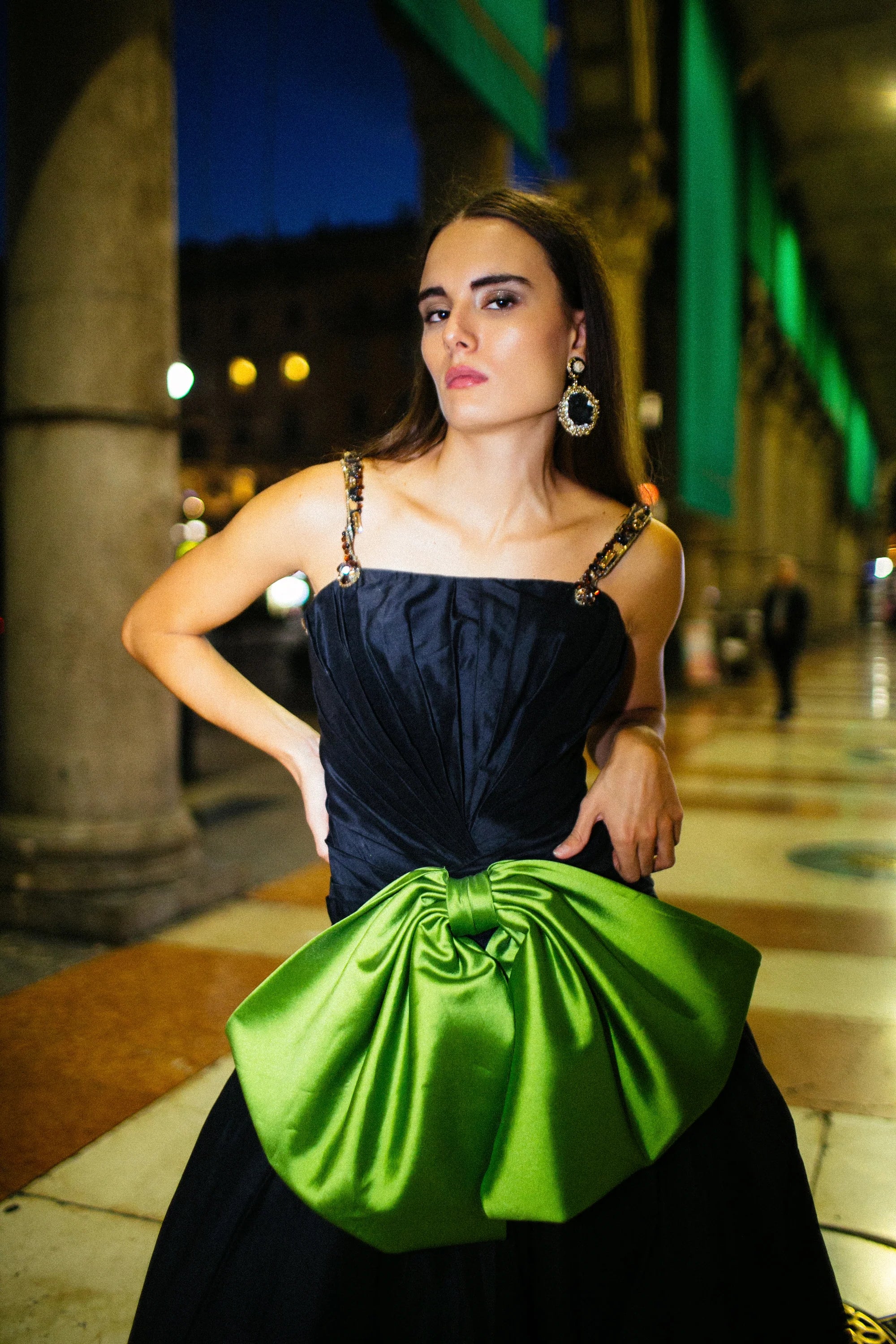 A navy gown with a large green satin bow gathered at the hip, photographed in Milan at night.
