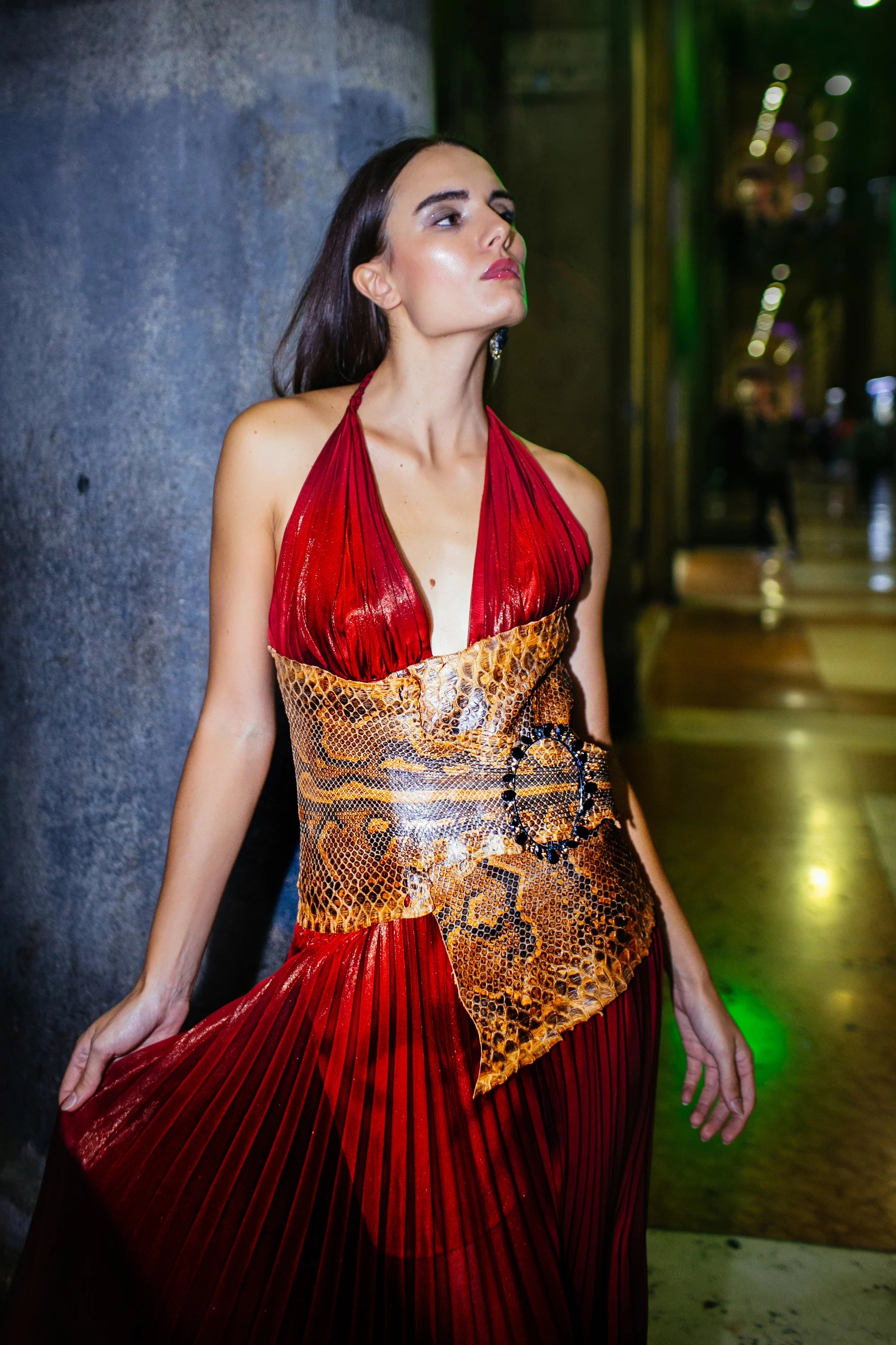 A red pleated gown with a gold worked bodice, photographed in the arcades of Milan at night.