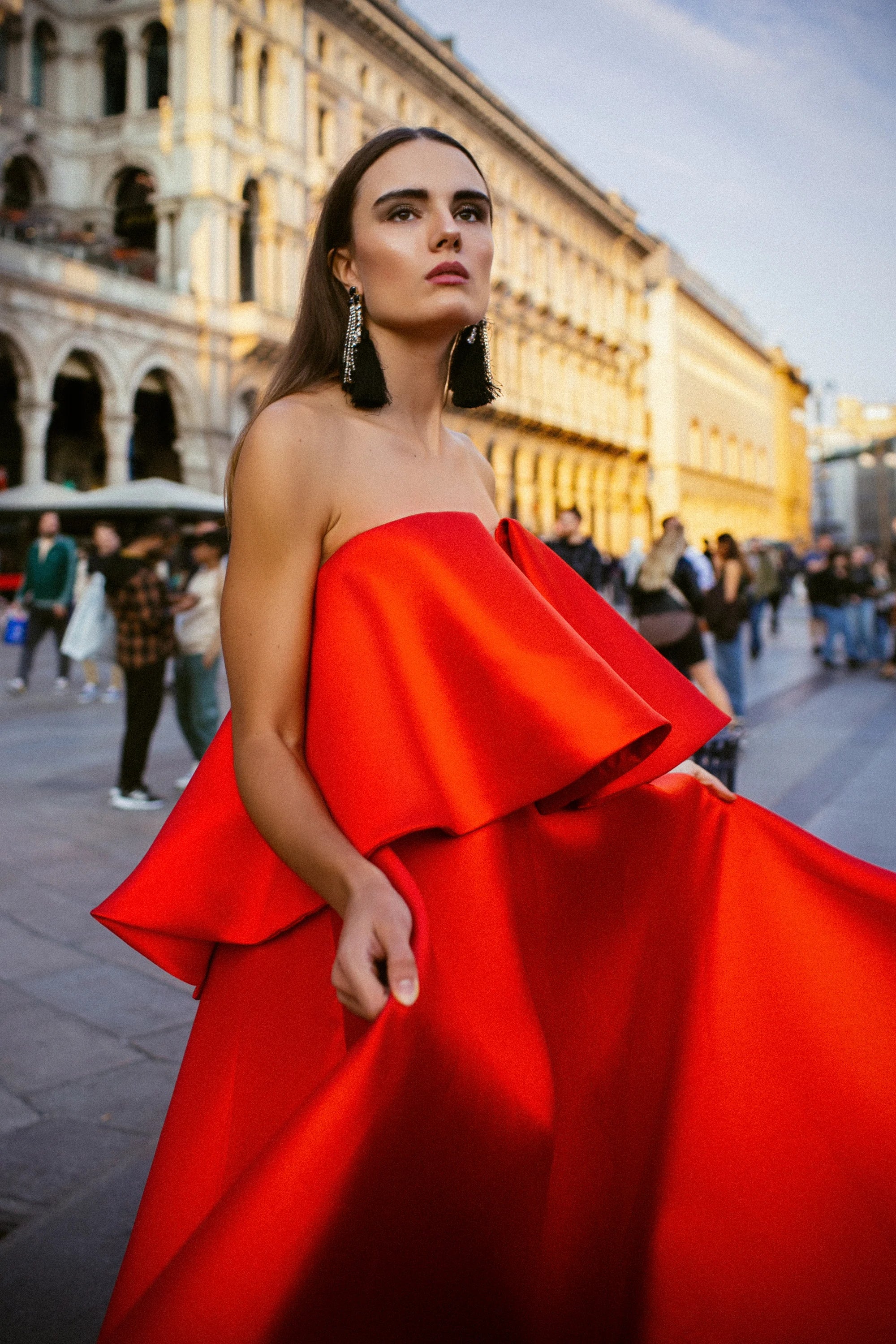 A red satin ballgown with a folded bow across the bust, photographed before the Duomo, Milan.