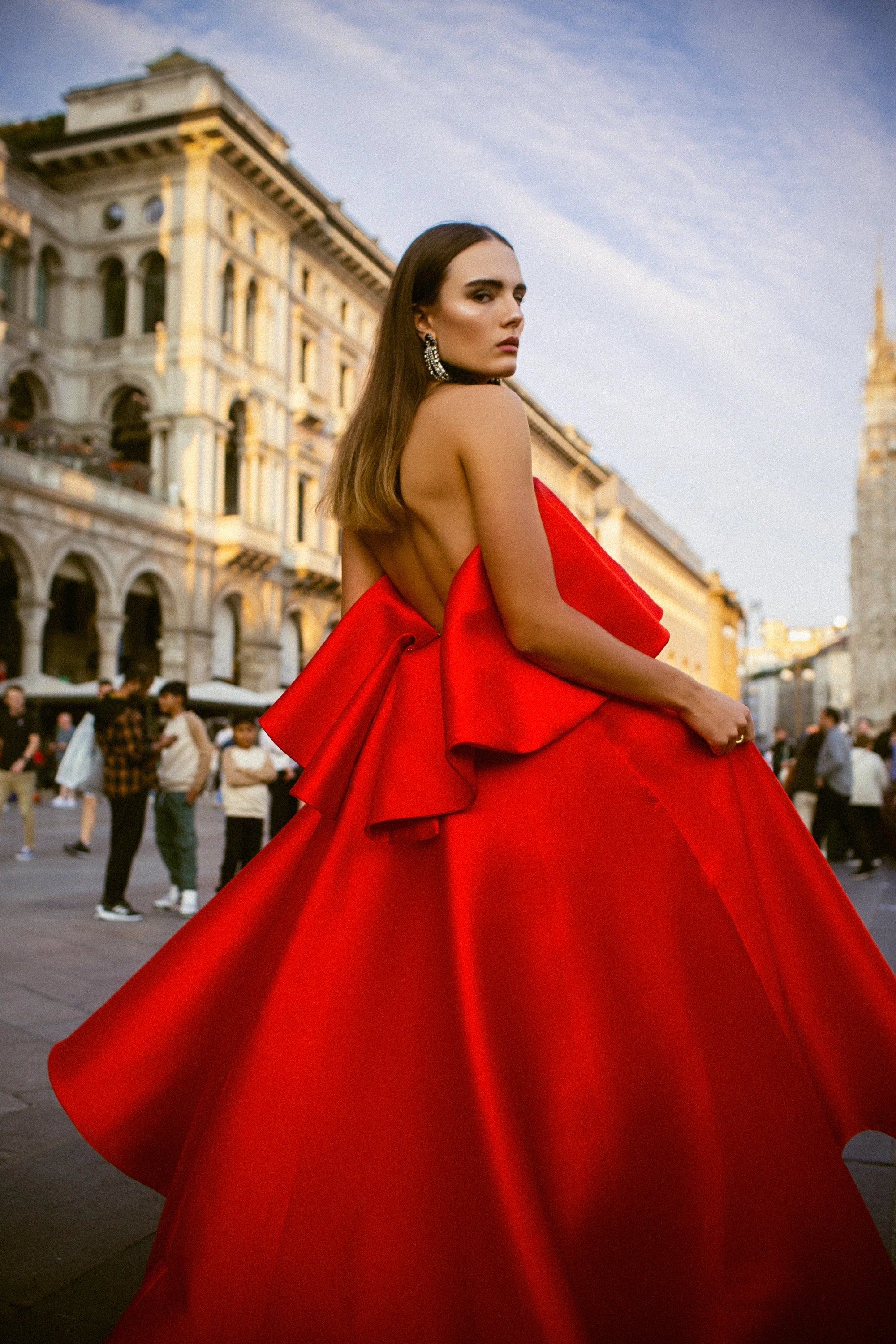 A red satin ballgown with a folded bow across the bust, photographed before the Duomo, Milan.