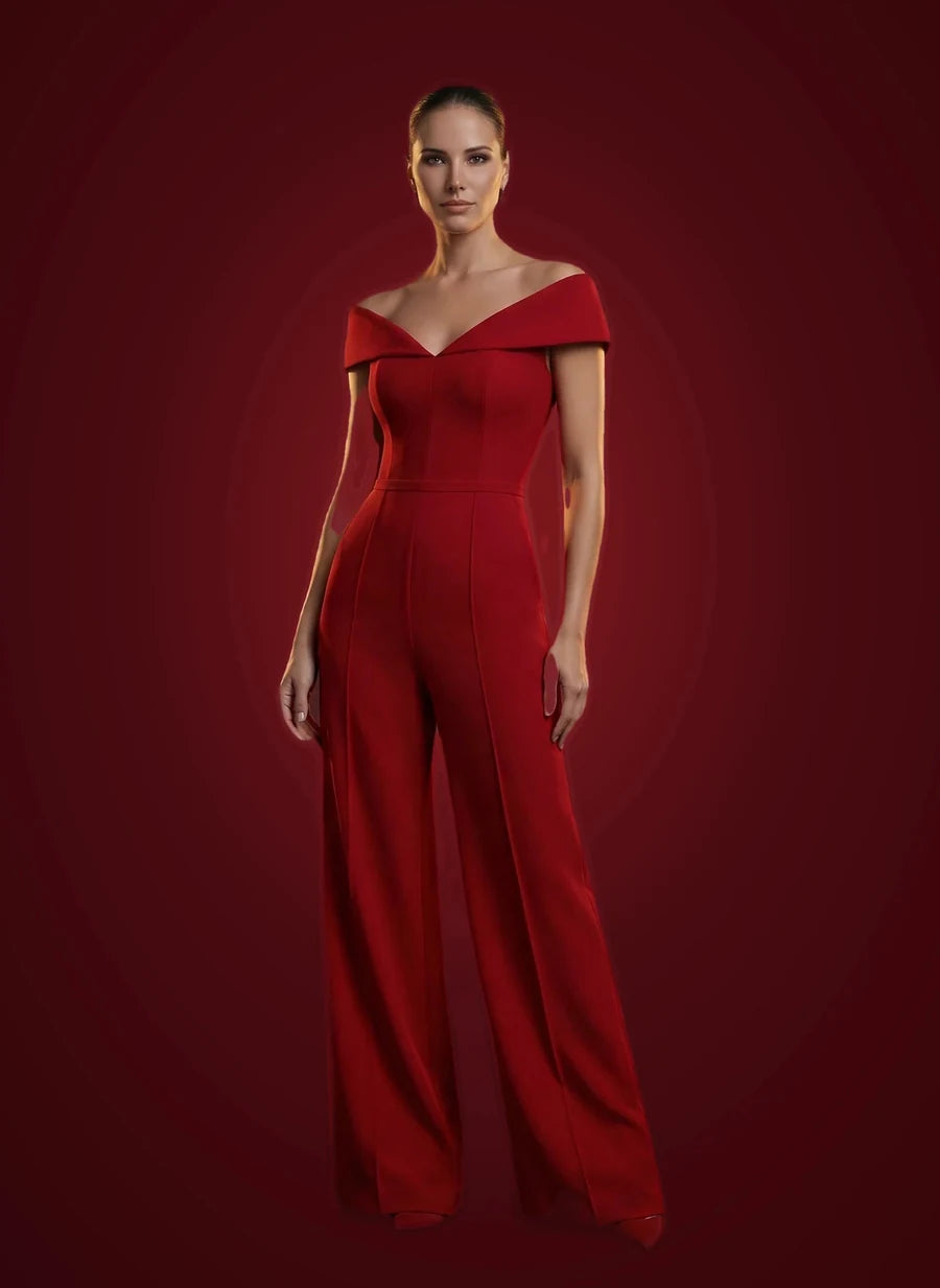 A red off-shoulder jumpsuit photographed against oxblood.