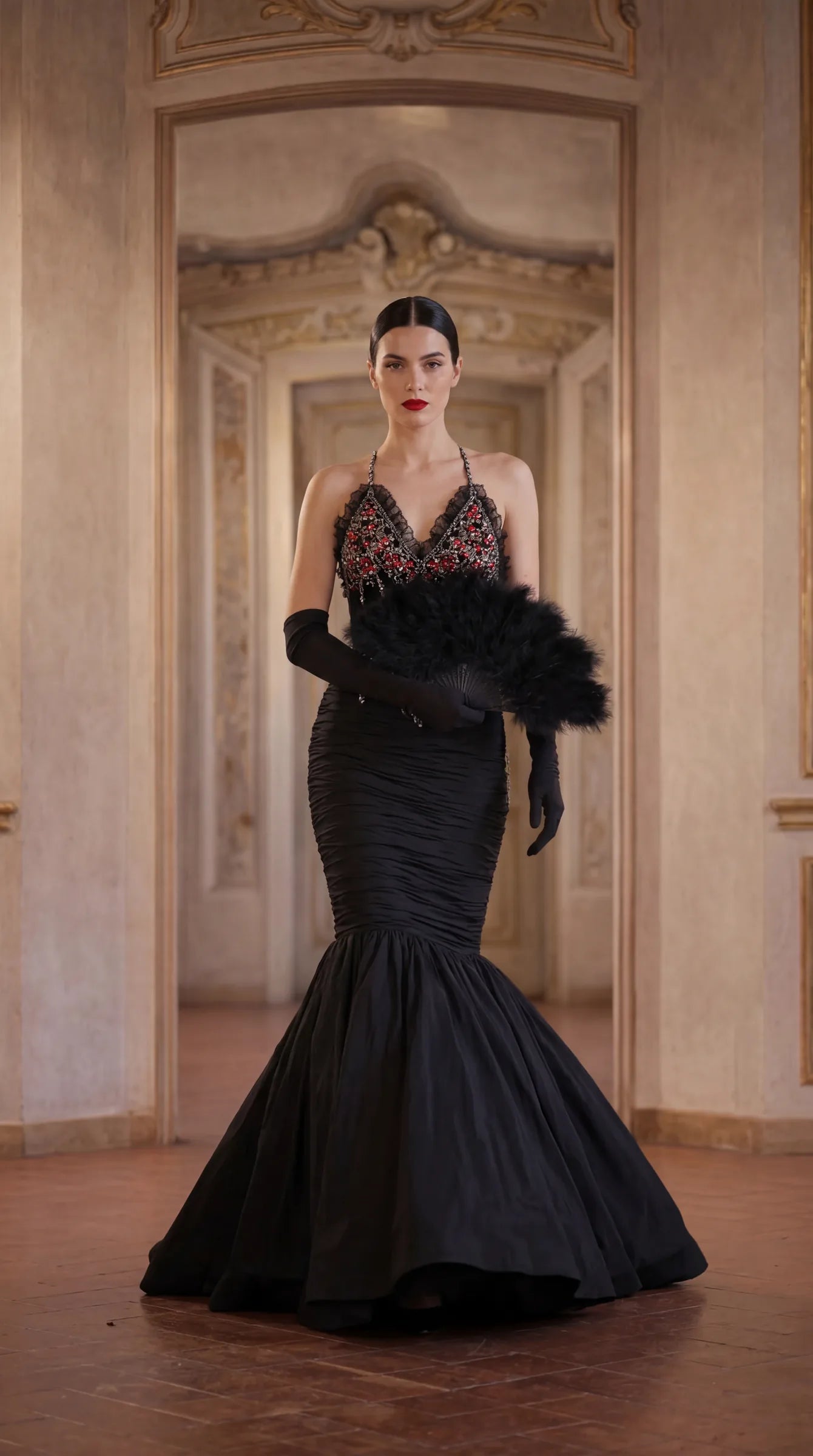A black mermaid gown, cut close through the body, photographed in a panelled room.