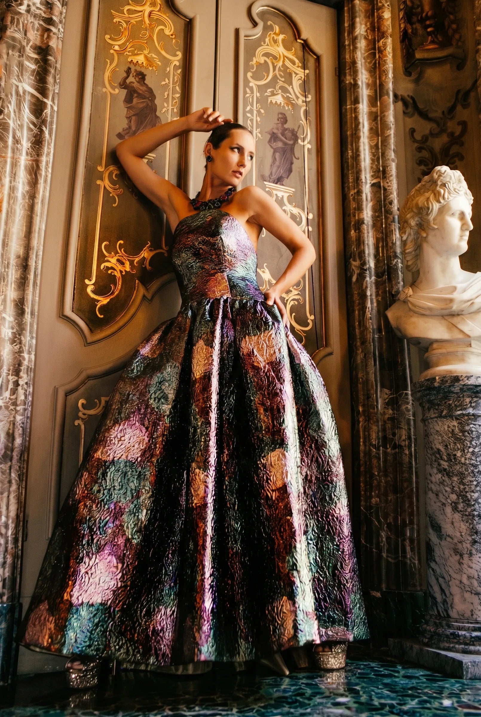 A ballgown in printed silk, photographed against the gilding of a palazzo wall.